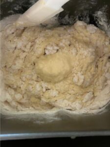 dough mixing in bread machine pan with spatula