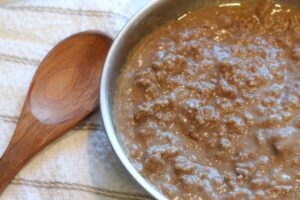 hamburger gravy in pan with wooden spoon and towel on side