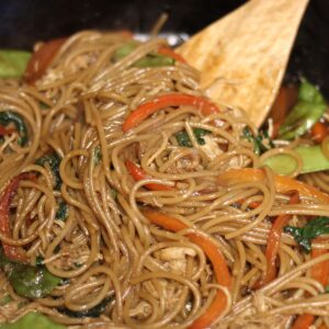 gluten free lo mein in cast iron pan with wooden spoon