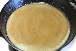 gooey caramel sauce ingredients combined together in cast iron pan