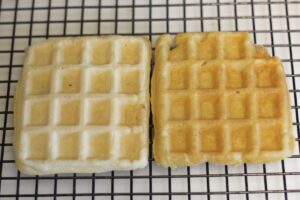 two waffles on cooling rack side by side.  the one on the left is lighter compared to the one on the right with a golden-brown hue.