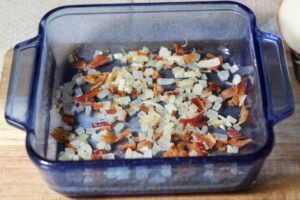 onions and bacon spread out in baking dish
