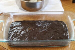 brownie batter spread out in glass baking dish