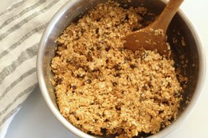 ingredients for peanut butter energy balls combined in a mixing bowl with a wooden spoon