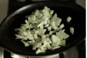 diced onion sauteing on a cast iron skillet