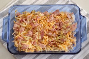 ingredients for breakfast casserole layered in glass casserole baking dish