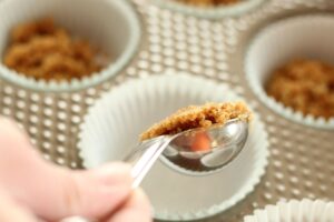 measuring graham cracker crust ingredients into muffin tin liners