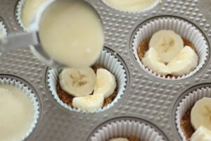 pouring cream filling on top of sliced bananas and graham cracker crust