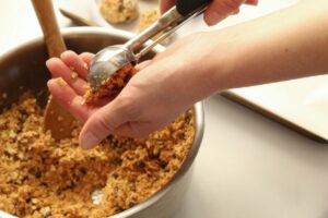 forming peanut butter energy balls in hand with cookie scoop