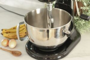 stand mixer with bananas, eggs, & measuring spoon alongside