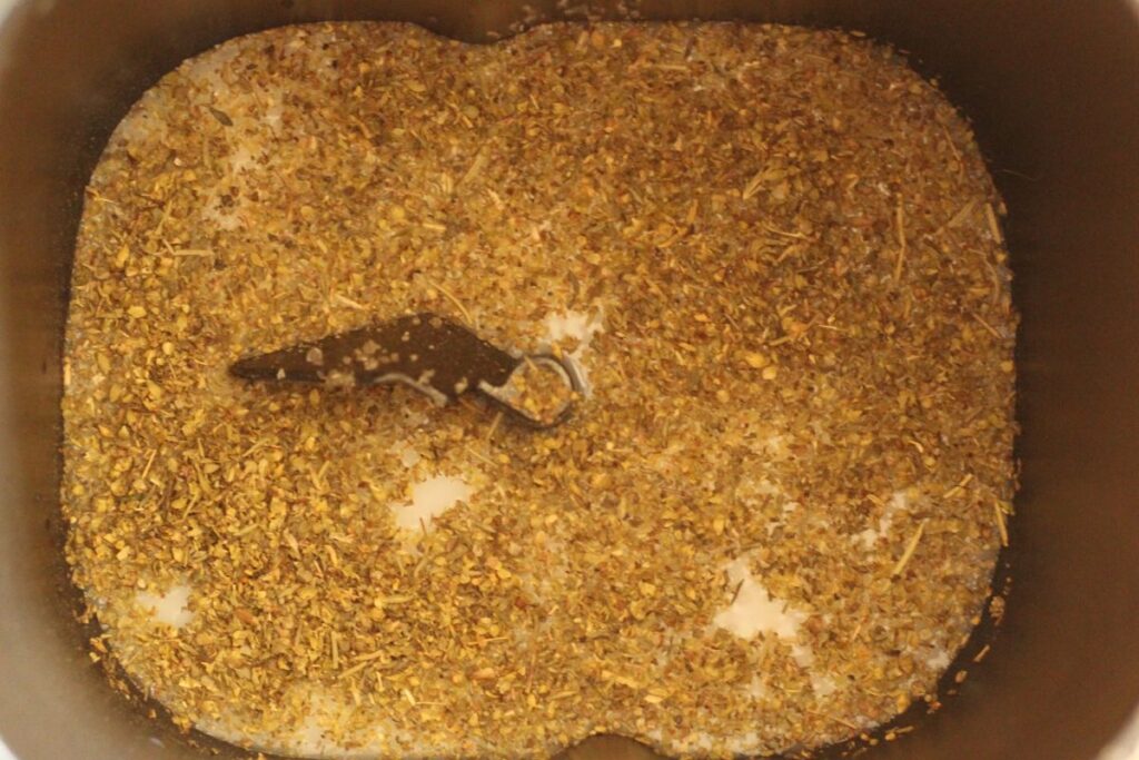bread machine pan with liquid ingredients and Italian herbs