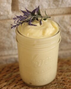 homemade whipped body butter in jar with a sprig of lavender on top