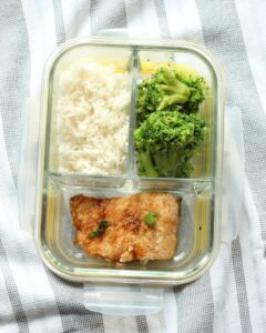 leftovers of maple glazed salmon in glass container with rice and broccoli