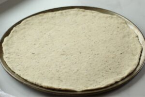 homemade pizza dough rolled out on pizza pan