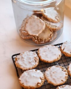 iced oatmeal cookies on a cooling rack and in a glass cookie jar