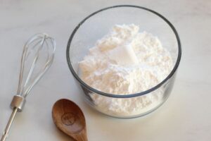 powdered sugar in bowl with whisk and measuring spoon alongside