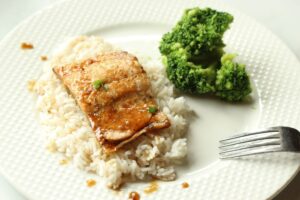 maple glazed salmon served on a plate over bed of rice with a side of broccoli