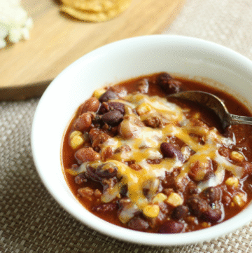 homemade crockpot chili in a bowl next to toppings