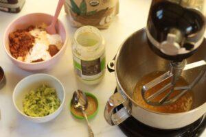 wet ingredients for grain free zucchini muffins in stand mixer with dry ingredients alongside.