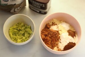 dry ingredients for grain free chocolate zucchini muffins in a bowl. shredded zucchini in a bowl alongside.