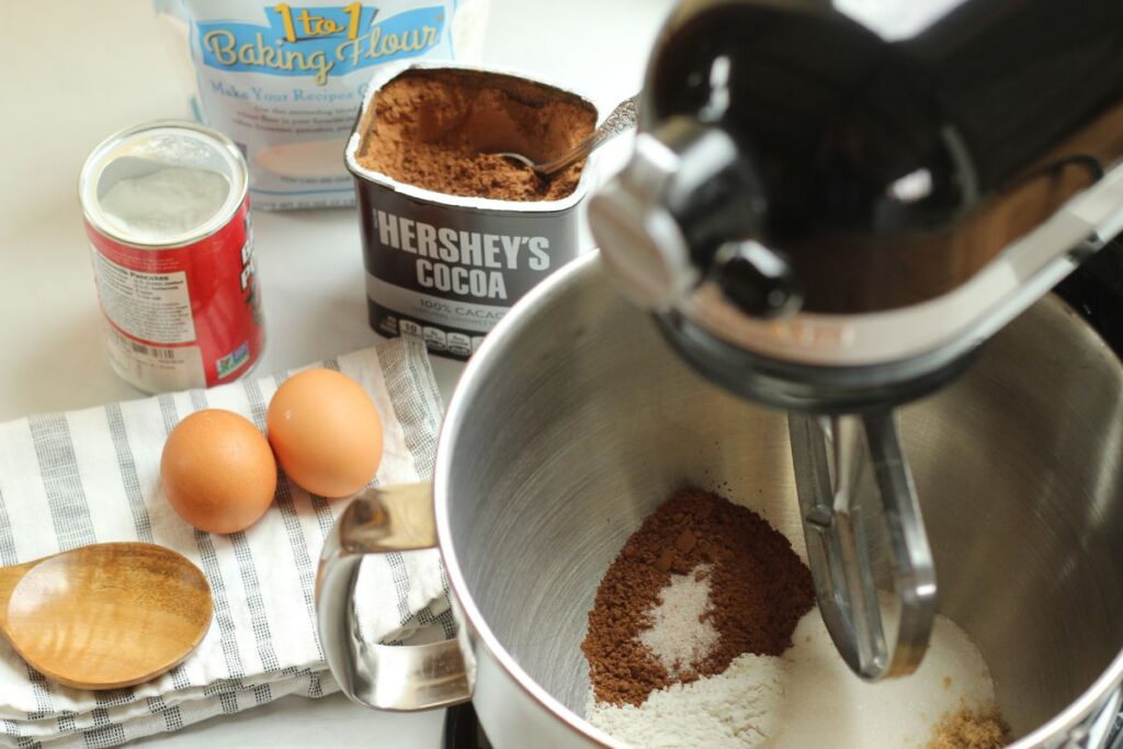 dry ingredients for gluten free brownies in stand mixer bowl with other ingredients alongside