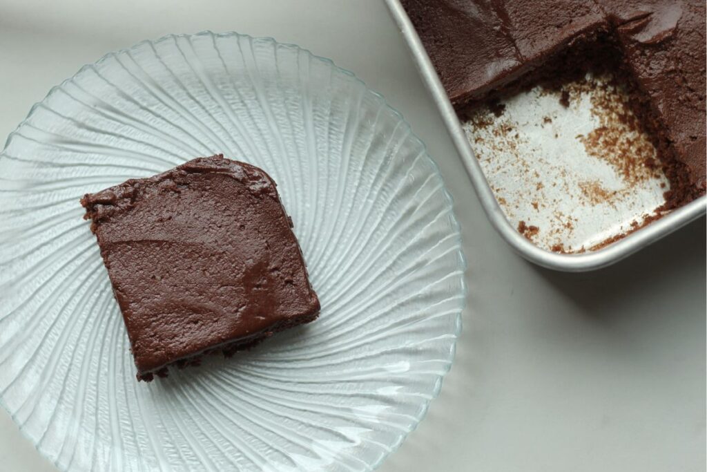 slice of gluten free brownie on glass plate next to pan
