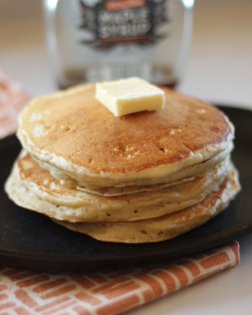 stack of golden brown pancakes with butter on top