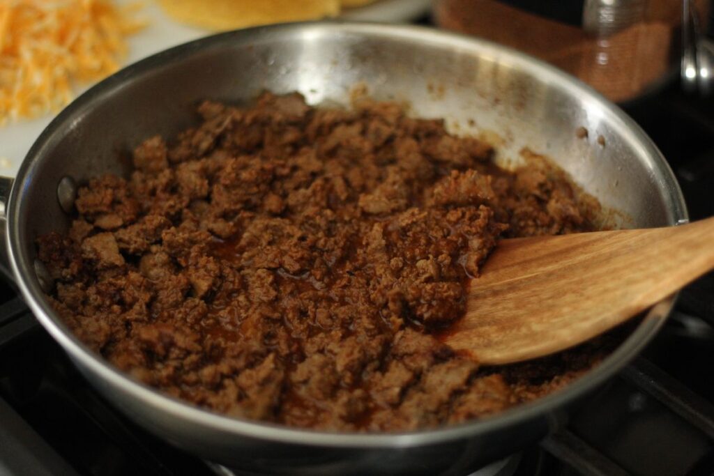 ground beef taco meat in saucepan with wooden spoon