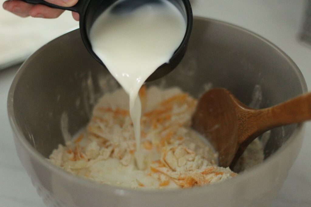 pouring milk into bowl of dry ingredients