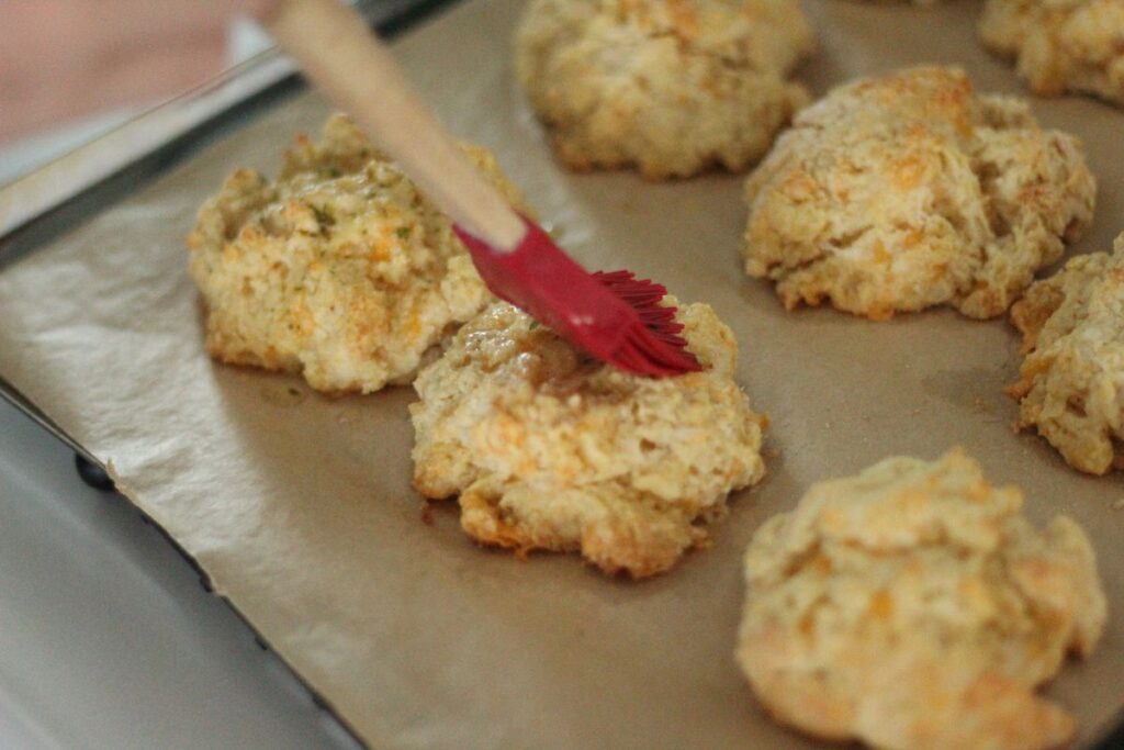 brushing freshly baked copycat Red Lobster biscuits with garlic butter topping
