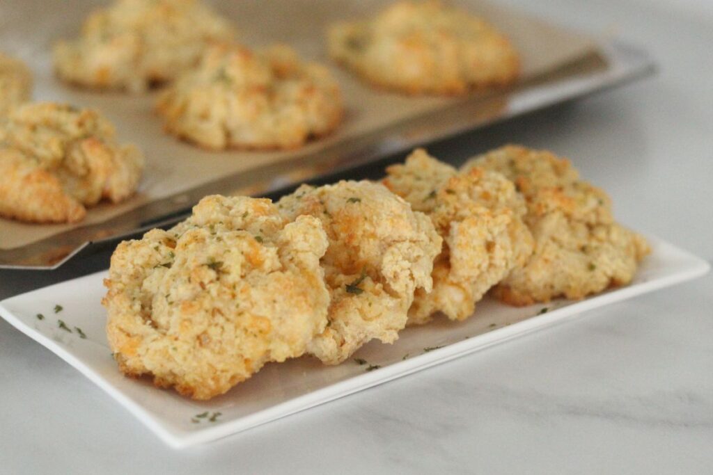 homemade Red Lobster biscuits on serving plate next to baking sheet