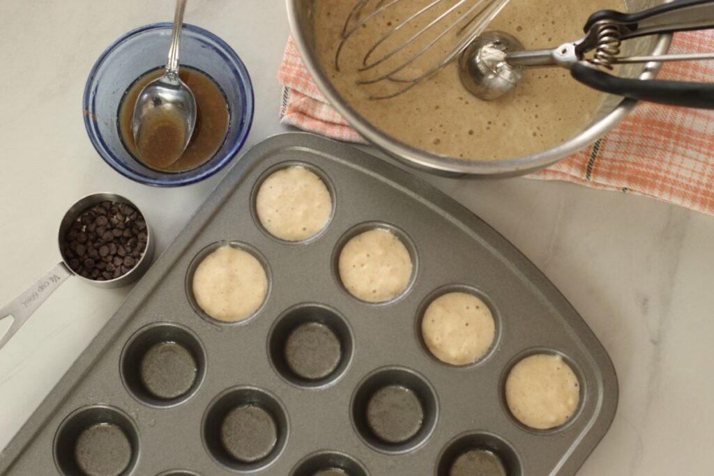 bowl of pancake mini muffins next to mini muffin tin with some of the cavities filled with batter