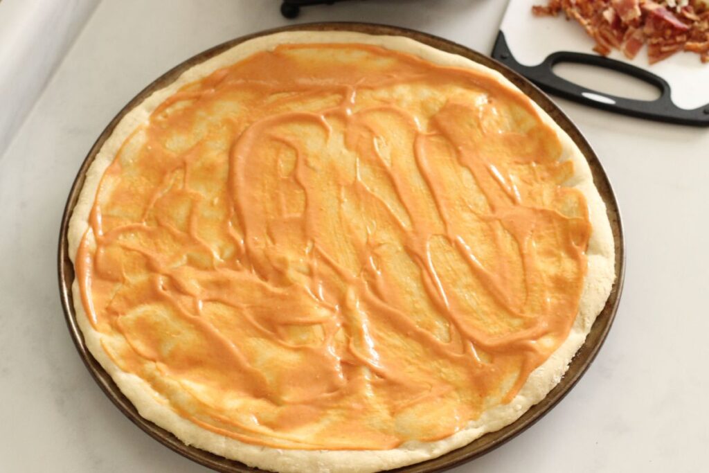 special sauce spread on homemade pizza crust for cheeseburger pizza