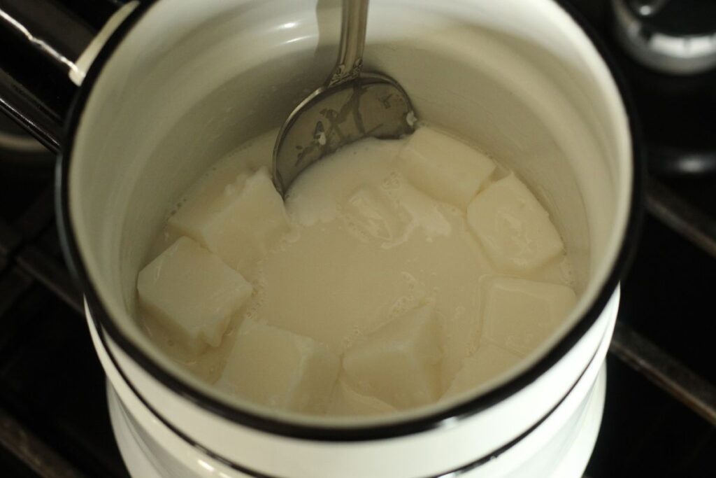 partially melted soap base in double boiler with metal spoon