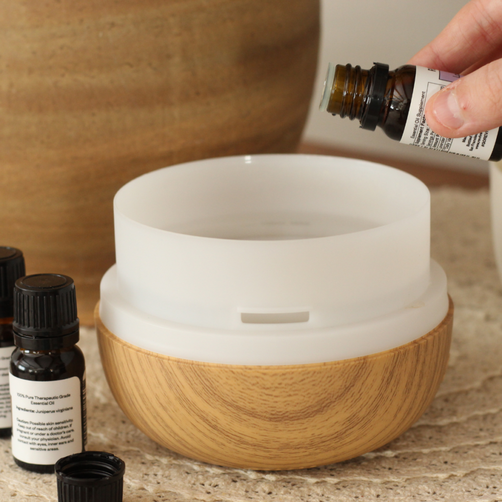 hand pouring essential oil into diffuser