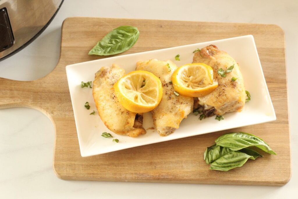 citrus & herb chicken thighs on a plater with lemon slices & basil