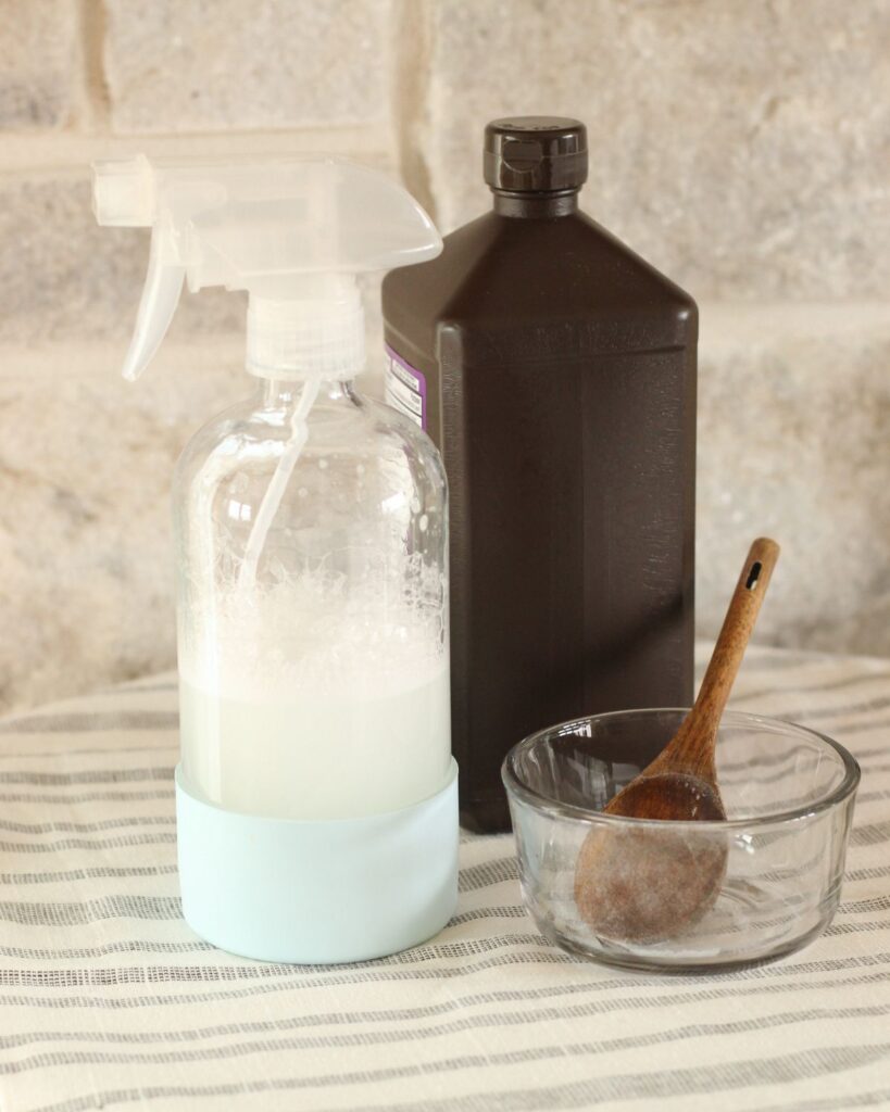 spray bottle of diy natural oven cleaner alongside a glass bowl and bottle of peroxide