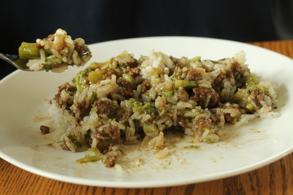 beef & broccoli stir fry on a plate with a fork holding up a bite of it
